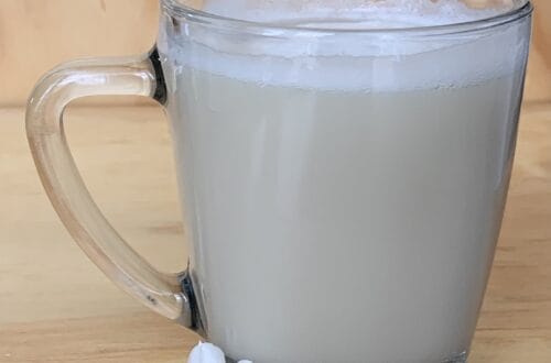 Glass mug with chamomile vanilla tea latte prepared with almond milk