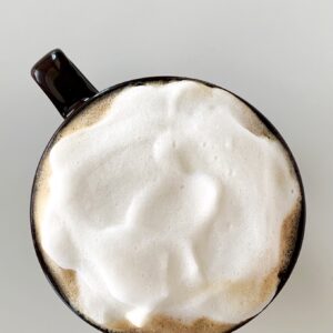 Overhead view of almond milk latte made with brown sugar syrup, topped with almond milk foam in a brown mug