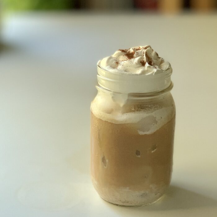 Coquito Iced Latte topped with whipped cream and cinnamon