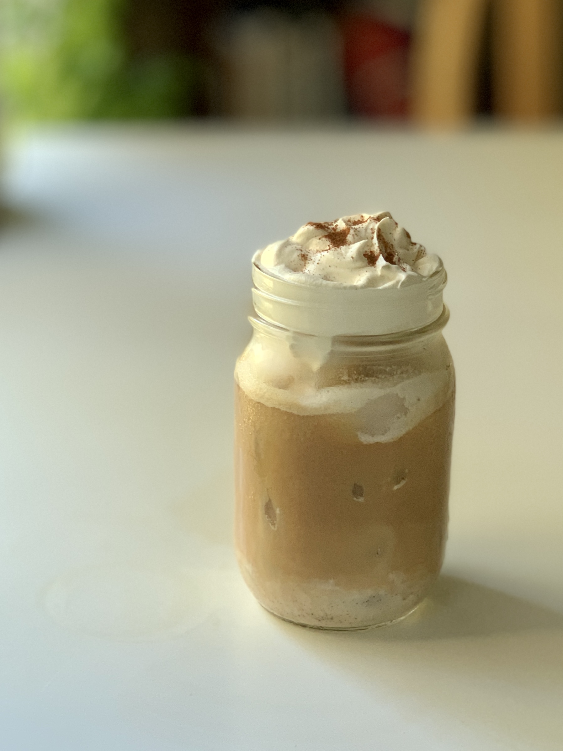 Coquito Iced Latte topped with whipped cream and cinnamon