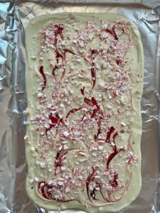 White chocolate with crushed candy canes on a baking sheet lined with foil