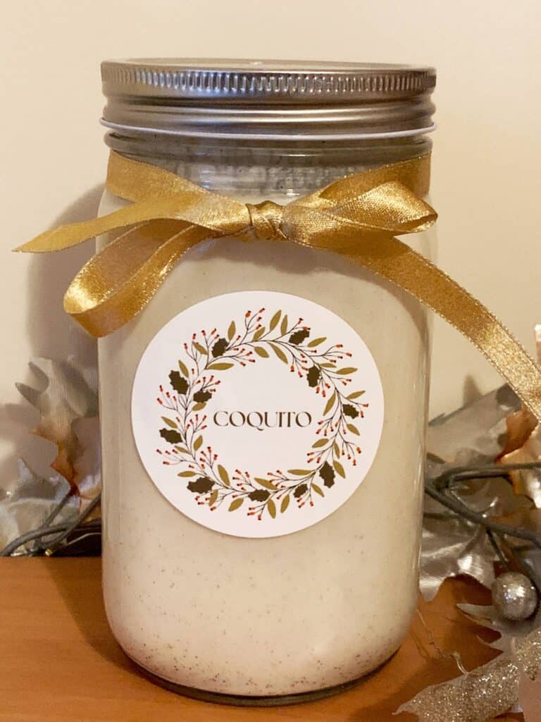 Homemade Coquito in a glass mason jar with gold ribbon