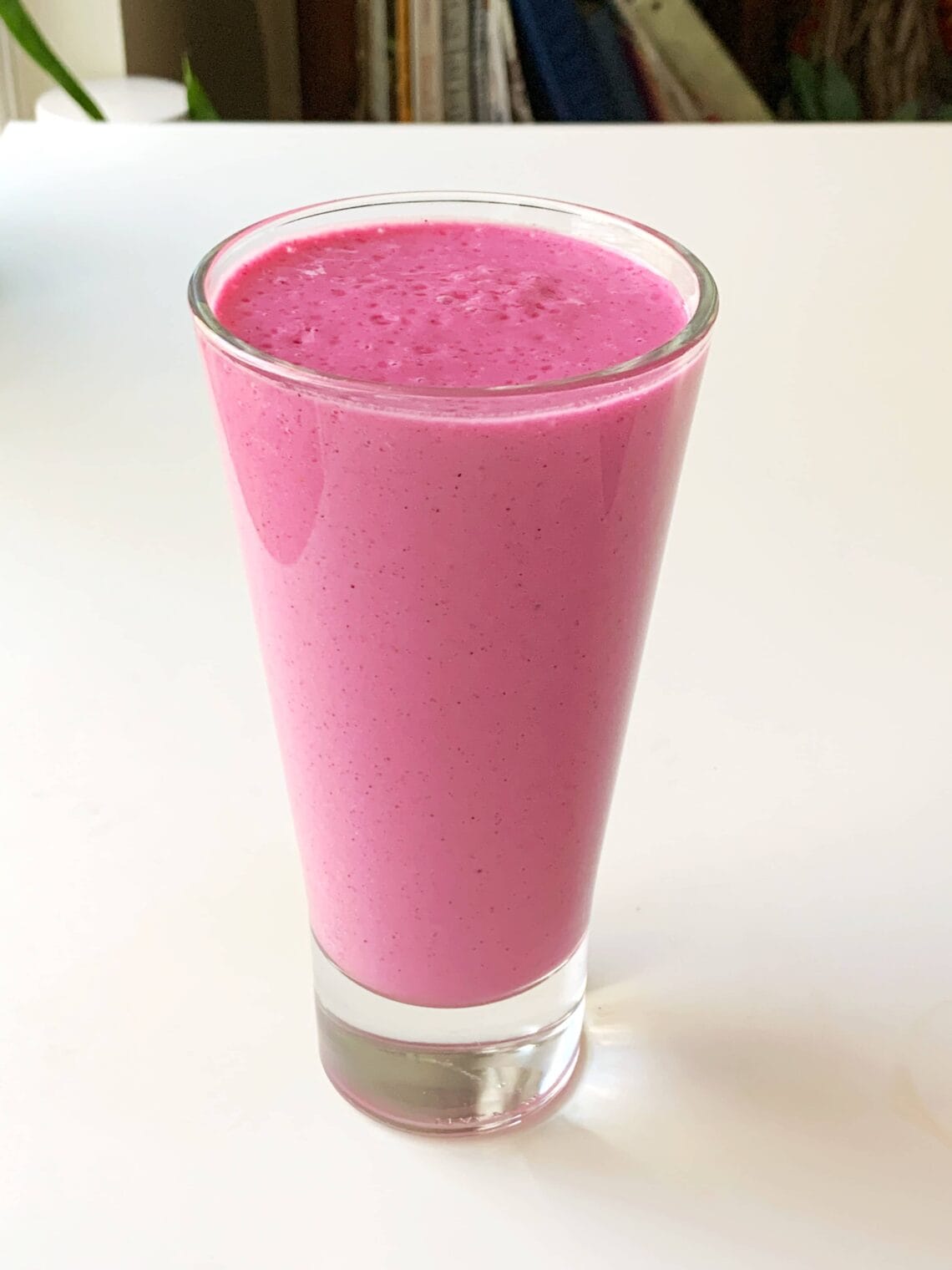 Pink dragonfruit and raspberry smoothie in a tall glass