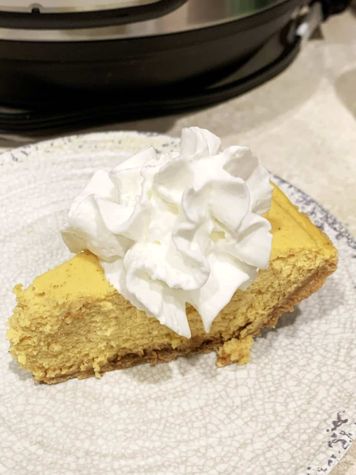 Slice of pumpkin cheesecake topped with whipped cream