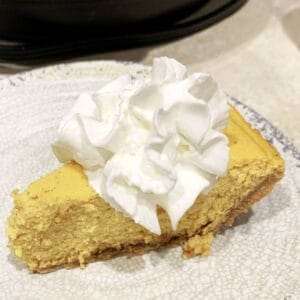 Slice of pumpkin cheesecake topped with whipped cream