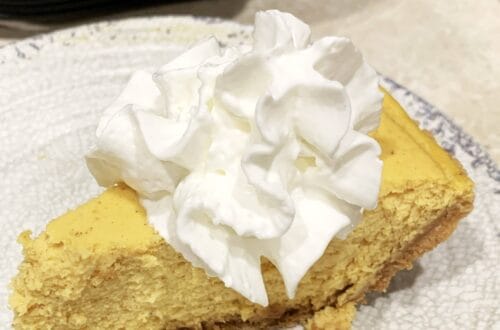 Slice of pumpkin cheesecake topped with whipped cream