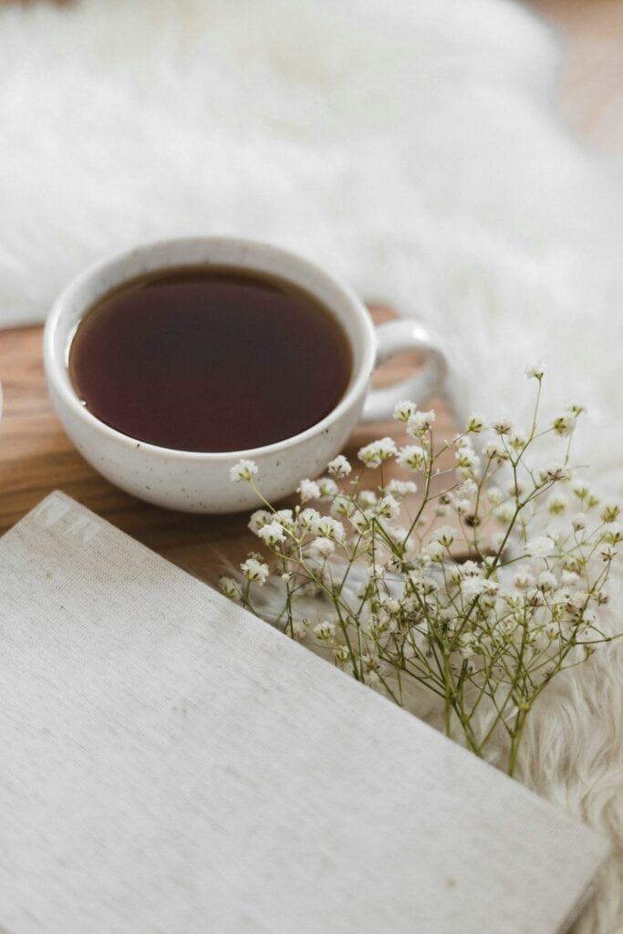 A cup of tea on a wooden cutting board with baby's breath flowers