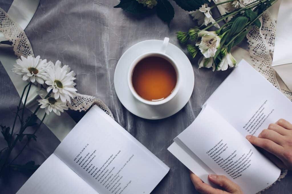 A cup of tea on a saucer with daisy flowers and books