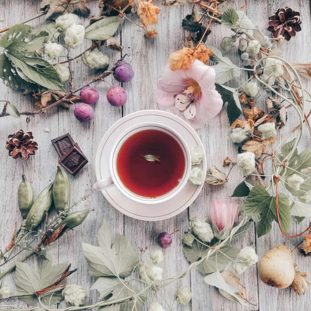 An overhead view of a cup of tea surrounded by floral elements