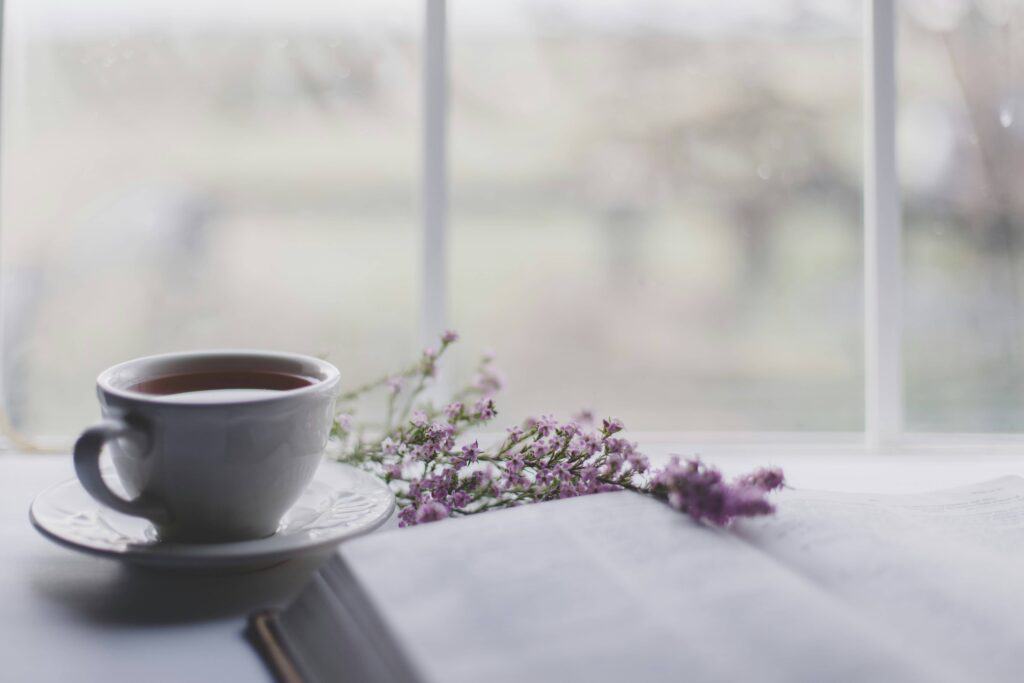 A cup of tea on a saucer with purple flowers