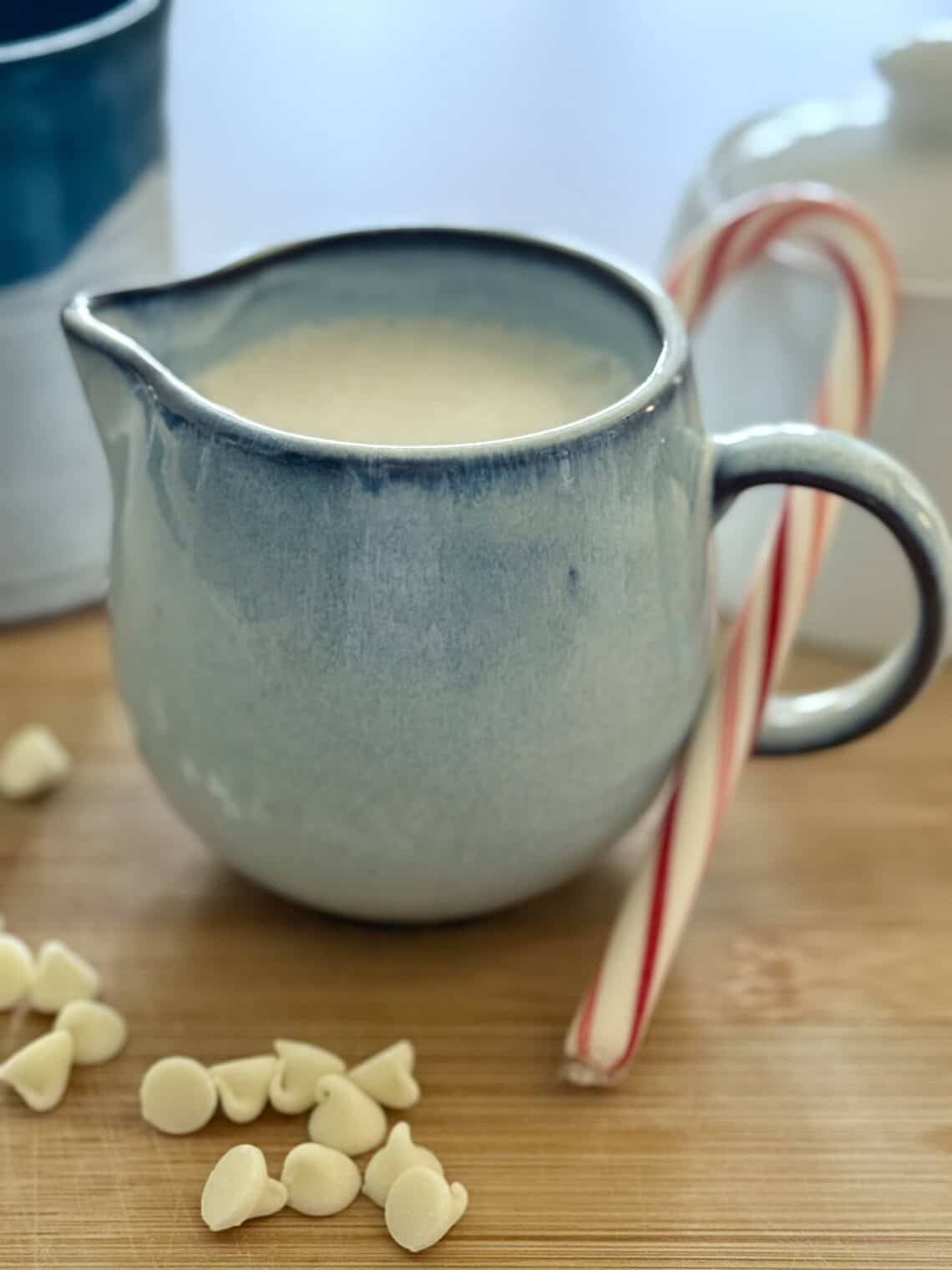 White Chocolate Peppermint Creamer in a blue ceramic creamer with white chocolate chips and peppermint candy cane