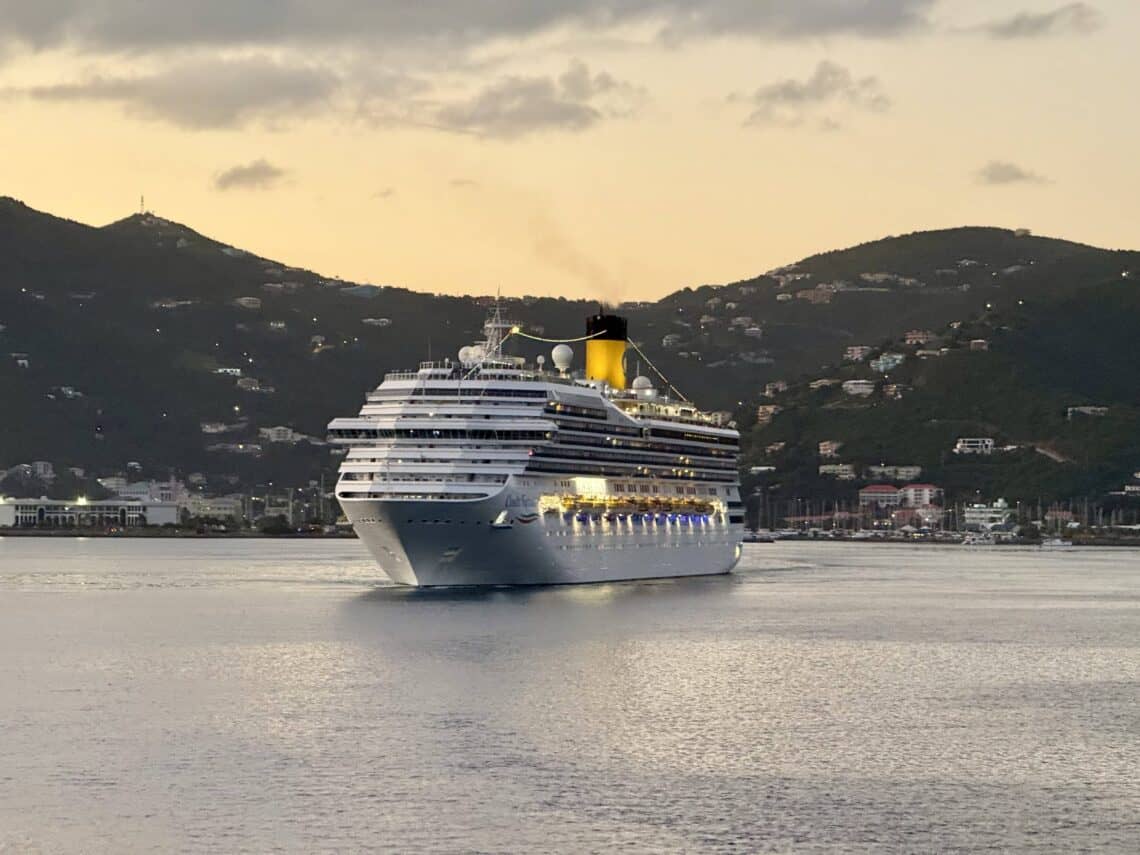 Cruise ship sailing at sunset with mountains in the background