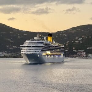 Cruise ship sailing at sunset with mountains in the background