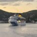 Cruise ship sailing at sunset with mountains in the background