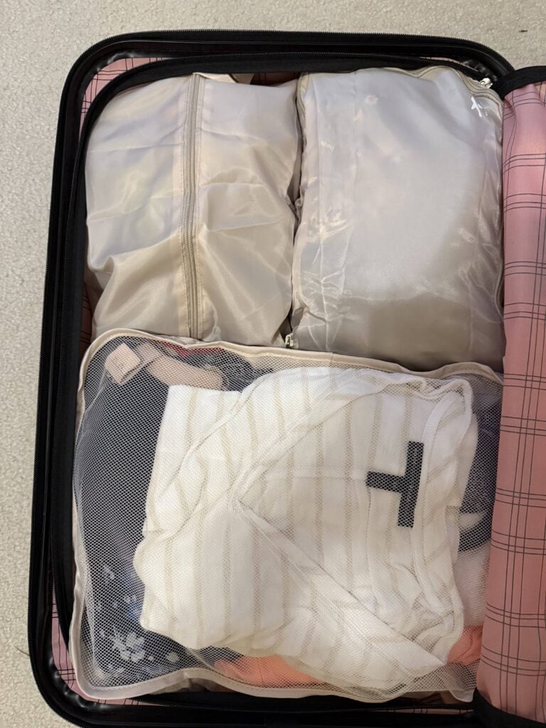 Packing cubes filled with clothes inside a pink suitcase