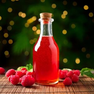 Raspberry Vanilla Syrup in a glass bottle with raspberries