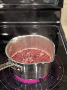 Raspberry vanilla syrup simmering in a saucepan on the stove.