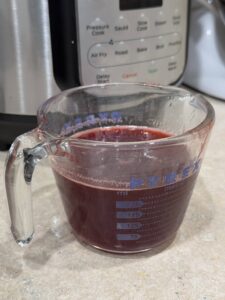 Raspberry Syrup cooling to room temperature in a glass Pyrex measuring cup.