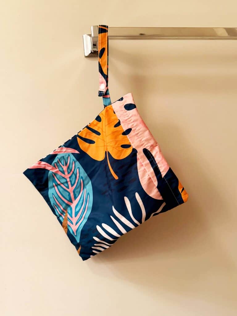 A colorful wet bathing suit bag with a tropical design, essential item to pack for a cruise